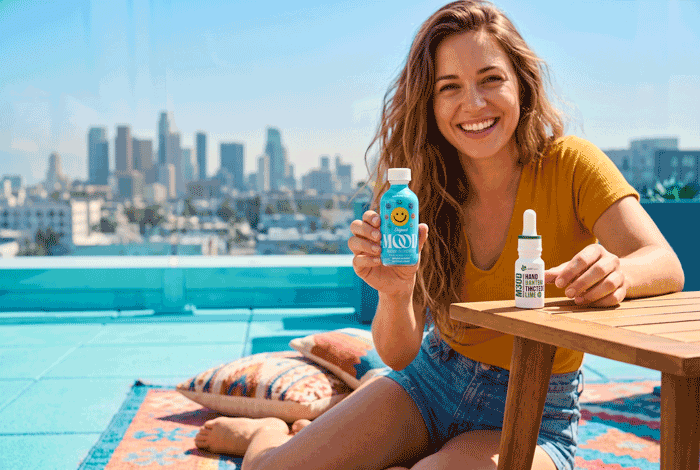 a woman sitting on a patio with a table and two bottles of liquid