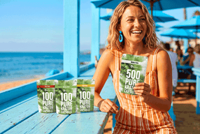 a woman smiling at a table with packages of kratom capsules