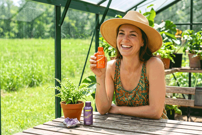 a woman sitting at a table holding a bottle of sunscreen